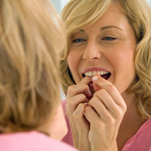 Blonde Woman Flossing in front of mirror