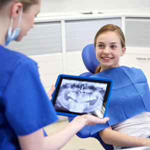 Teenage Girl on Dental Chair While Dentist Looks at her Dental Xray Result