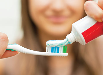 Woman placing toothpaste on toothbrush