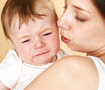 Mother carrying child who is crying due to teething